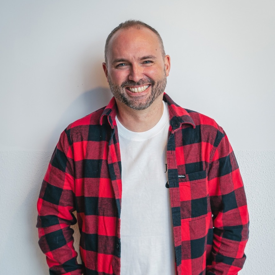 Daniel Honey smiling, wearing a red and black checked shirt